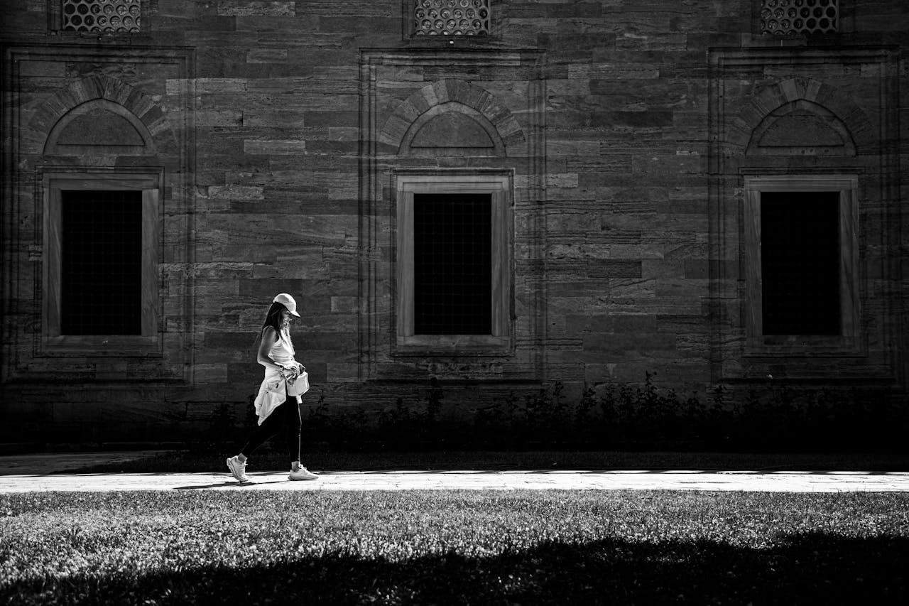 A woman walks past a historic building in Istanbul, captured in striking black and white.